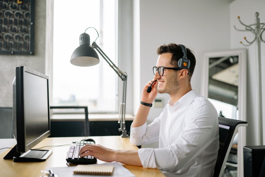 Collaborateur équipé d'un casque téléphonique répondant à un appel depuis son poste de travail
