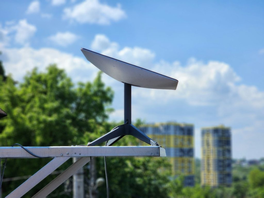 Antenne satellite Starlink installée sur un mât, devant des immeubles