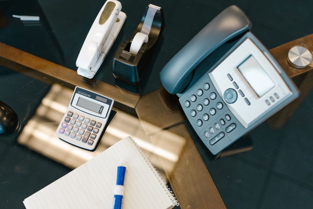 Téléphone IP de bureau à côté d'une calculatrice, pour estimer le coût d'un standard téléphonique